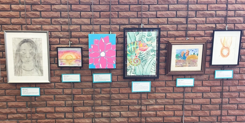 Gallery Dundas: Teen Art Show different paintings and artworks hung on a brick wall