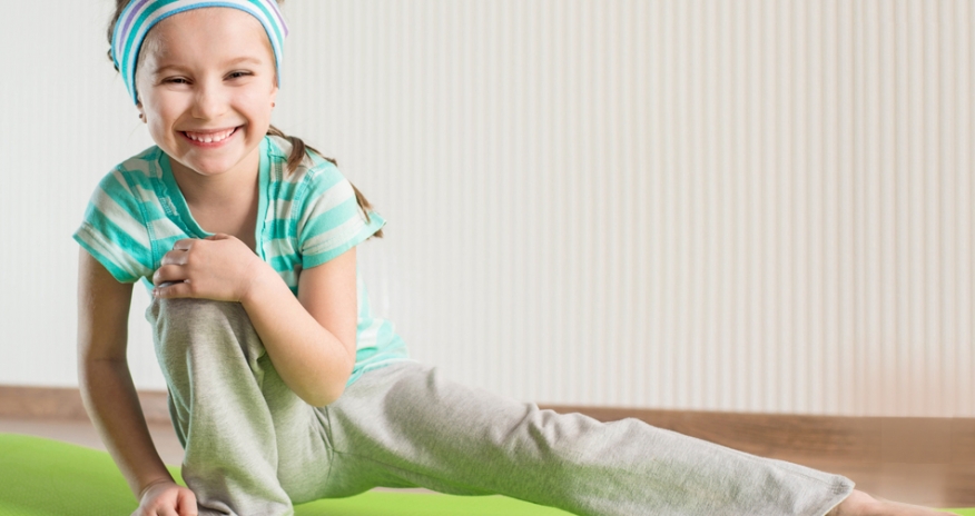 Health and Wellness Programs for Kids Young girl in exercise clothes stretching on a yoga mat