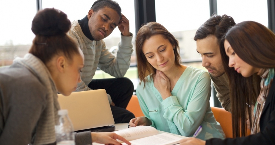 Homework Help Teens at a table looking at a book