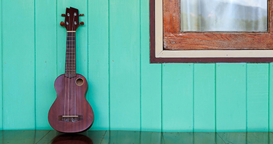 Learn how to play the ukulele photo of a ukulele against a wall