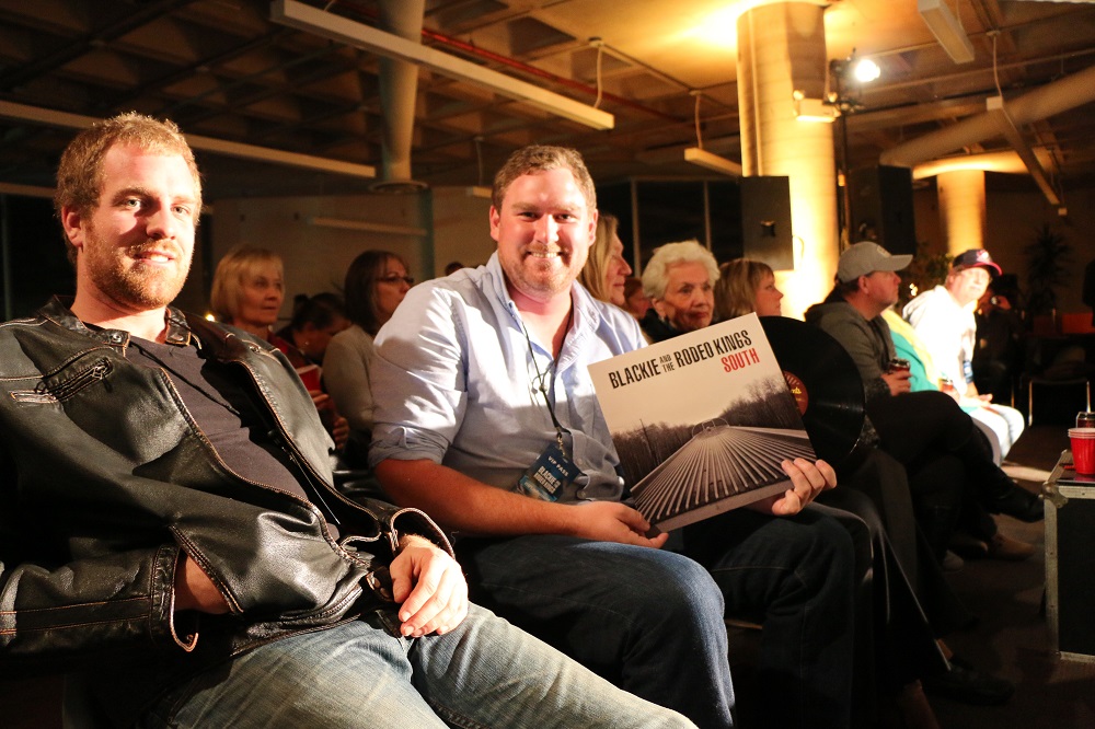 Photo of an audience member holding an album at the Photo of VIP passes at the Blackie and the Rodeo Kings concert