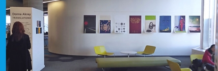 Woman reading description of art posters on a far wall