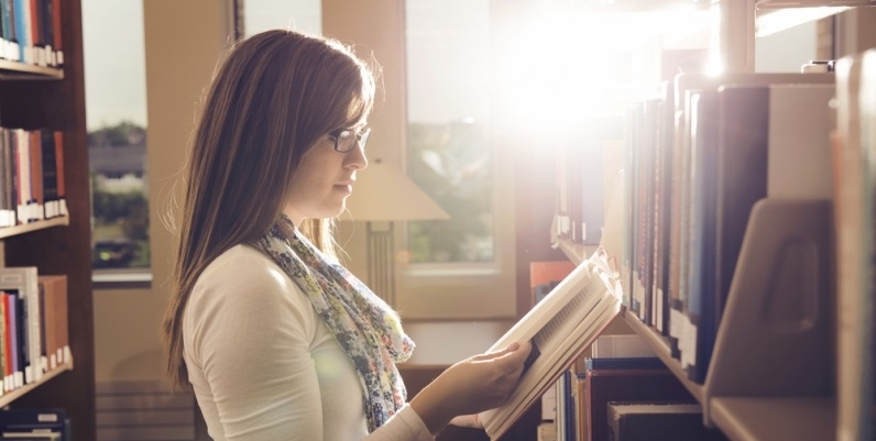 Woman reading a book in aisle