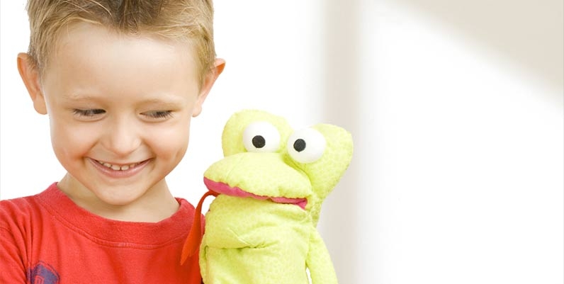 Little boy standing beside a hand puppet