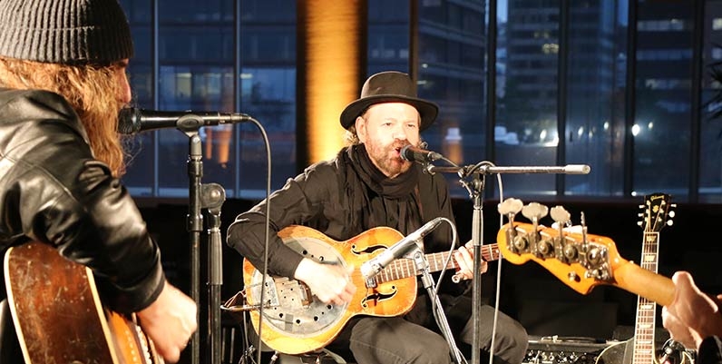 three musicians on a stage singing and playing guitar