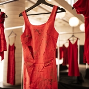 Larger red dress and smaller red dress in focus hanging on clothing rack.