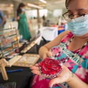 Vendor holding a red rose beadwork with white and black accents