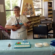 a photo of a woman with a ukulele and a table with cake