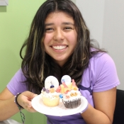 a girl holding a plate of cupcakes