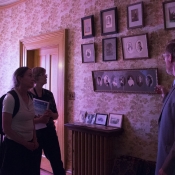 A small tour group looks on at pictures of the Whitehern family during a tour