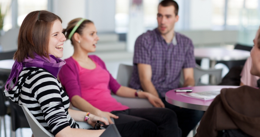 Group of teens at a table looking at a book Group of teens at a table looking at a book